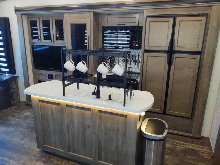 RV rental's modern kitchen: island with sink, microwave, large fridge, and ample cabinet storage.. Forest River Sabre 2021