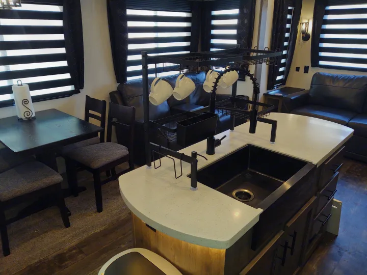 Spacious RV rental interior: dining area, kitchen island with sink, and living space with sofa. Modern and functional design.. Forest River Sabre 2021