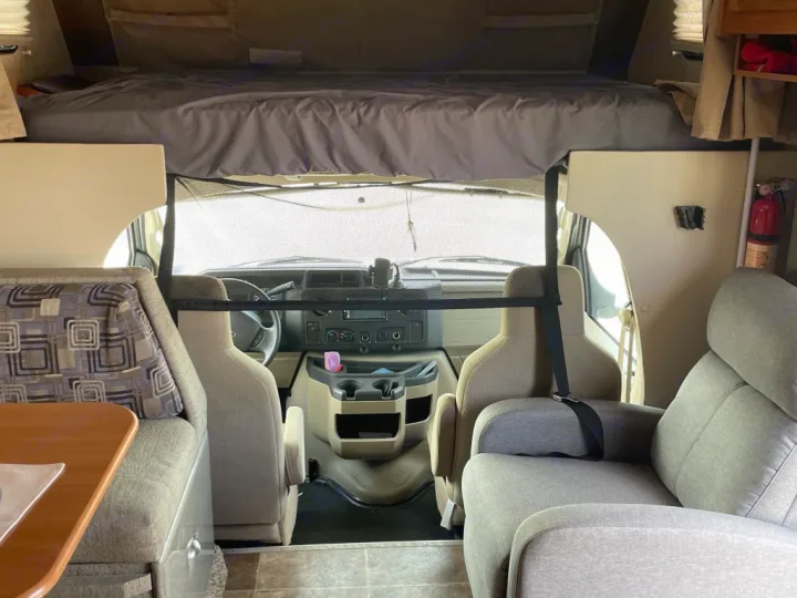 Inside this rv rental, a view from the back shows the front cab, an overhead bunk, and comfortable living area seating.. Adventurer Adventurer Motorhome 2017
