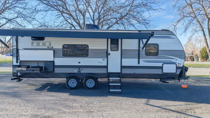 A modern Puma XLE travel trailer with an extended awning and outdoor kitchen, perfect for an RV rental getaway.. Forest River Palomino Puma XLE 2022