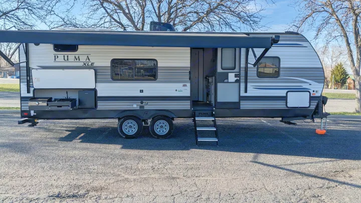 This Puma XLE travel trailer, possibly an RV rental, features an extended awning and outdoor kitchen, perfect for camping.. Forest River Palomino Puma XLE 2022