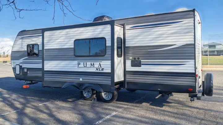 A PUMA XLE travel trailer, ready for rv rental, is parked with its slide-out extended under a clear sky.. Forest River Palomino Puma XLE 2022