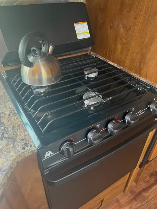 This RV rental kitchen features a Wedgewood Vision stovetop with a kettle, ready for hot drinks on your road trip.. Outdoors RV Creekside 2017