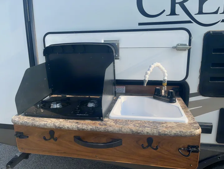 This RV rental features a convenient outdoor kitchen with a two-burner Suburban stove and sink for easy cooking.. Outdoors RV Creekside 2017