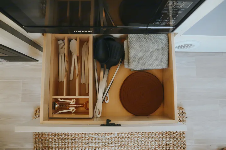 Organized RV rental kitchen drawer with white utensils, cooking tools, corkscrew, & towel, ready for your adventures.. Airstream Bambi 2023