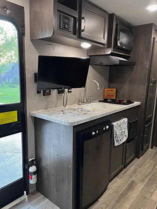This RV rental's well-appointed kitchen features a TV, microwave, sink, stove, and fridge, ready for your next adventure.. Jayco Jay Flight 2021