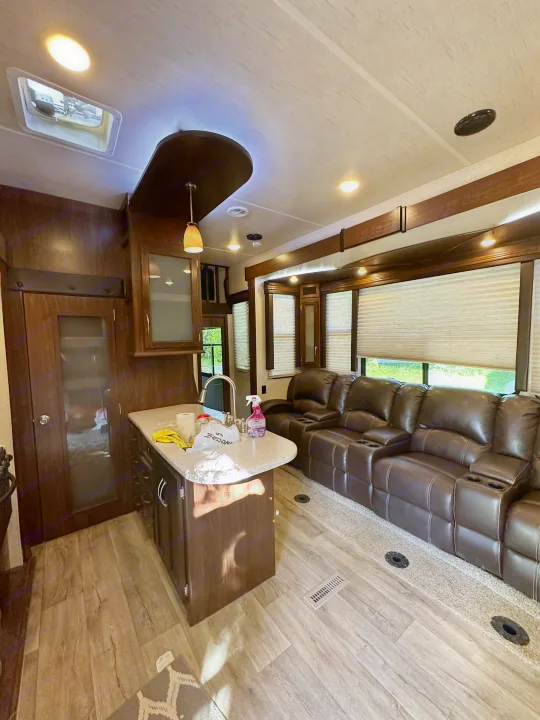 Spacious RV rental interior with a cozy living area featuring dark recliners, a modern kitchen island, and wood accents.. Heartland Torque 2018