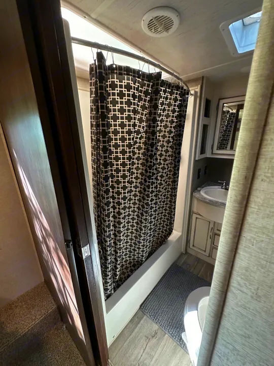 An interior shot of a functional RV rental bathroom, equipped with a shower (left), sink vanity, and toilet, ensuring travel comfort.. Heartland Torque 2018