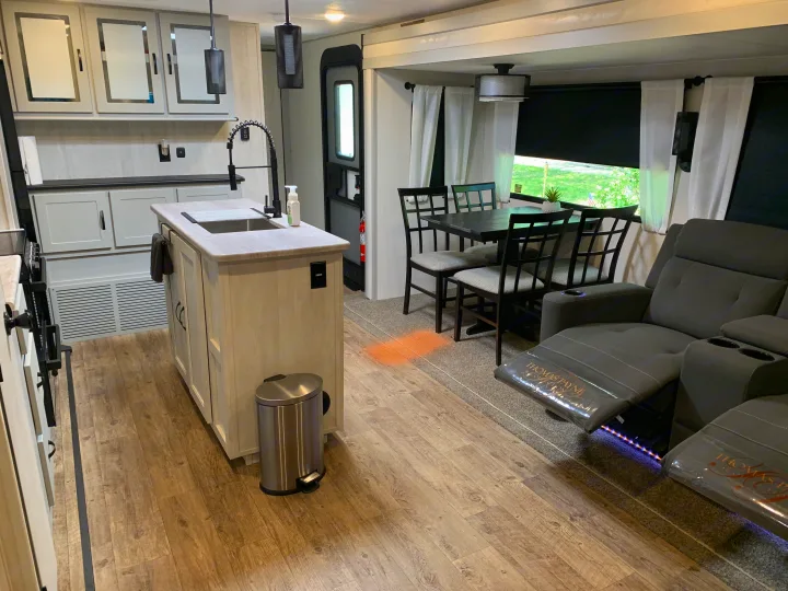RV rental: Bright, modern interior with kitchen island, dining area, and cozy recliner sofa.. Forest River Vibe 2023