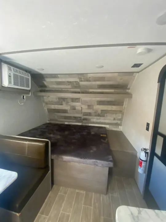 Cozy RV rental interior featuring a convertible dinette/bed, portable AC, and safety essentials like a fire extinguisher.. Dutchmen Coleman Lantern LT 2022