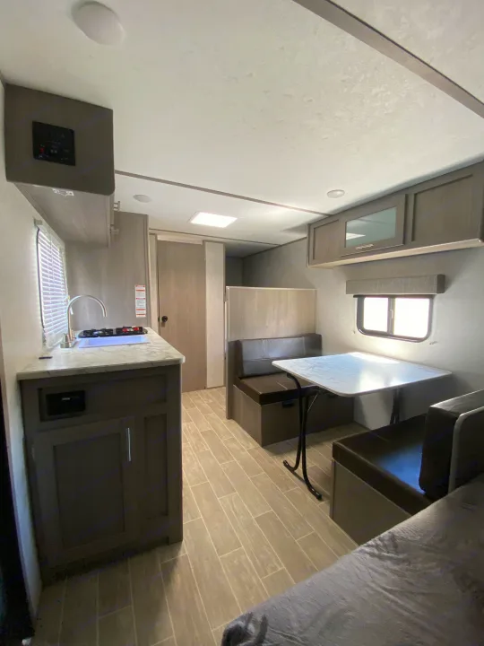 Bright rv rental interior with kitchen, dinette area featuring table and bench seating, and light wood-look flooring.. Dutchmen Coleman Lantern LT 2022