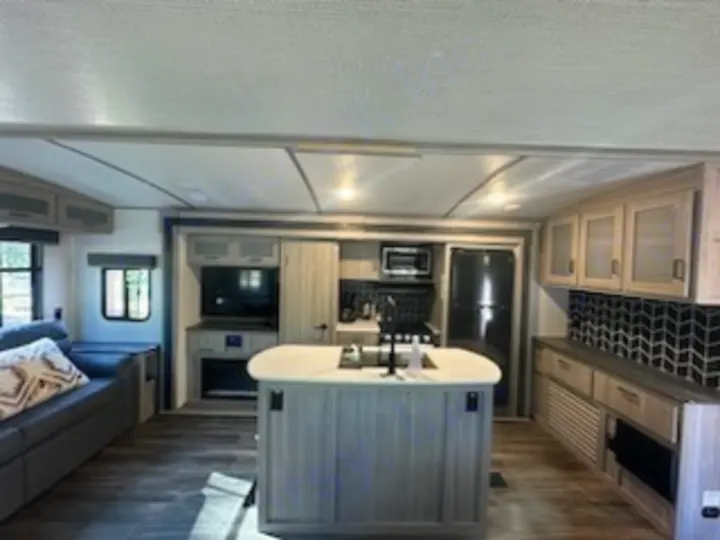 Spacious RV rental interior: modern kitchen island, living area, and full amenities for your mobile travel accommodation.. Keystone RV Passport GT 2022