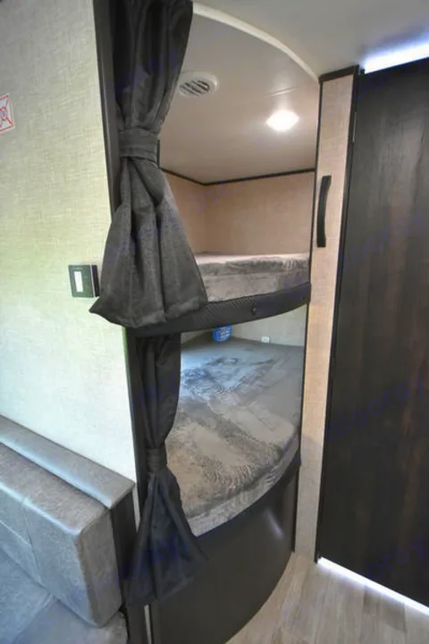 Cozy RV rental interior shows two stacked bunk beds with privacy curtains, offering comfortable sleeping space for travelers.. Jayco Jay Flight SLX 2020