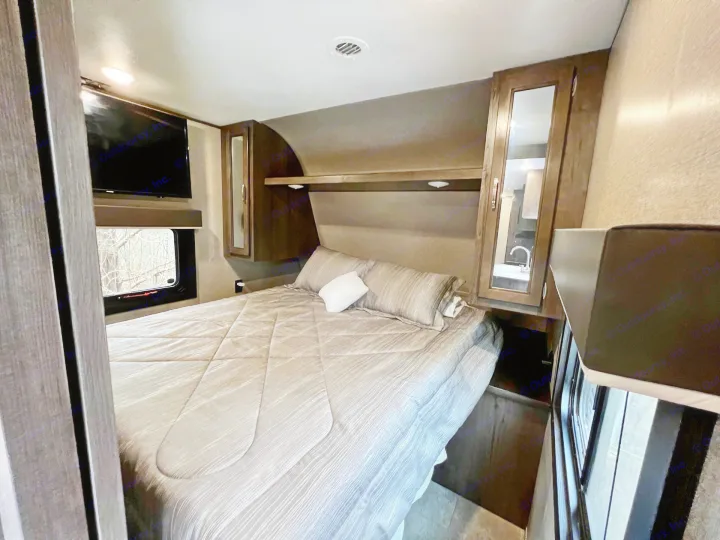 Cozy RV rental bedroom featuring a spacious bed, wall-mounted TV, and convenient overhead storage for a comfortable stay.. Jayco Jay Flight SLX 2020