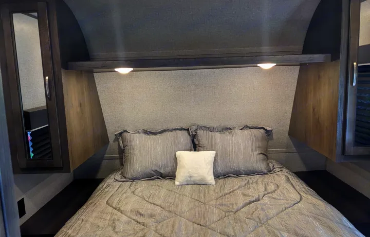 Cozy grey bedroom in an RV rental, featuring a comfortable bed, overhead lighting, and compact storage.. Jayco Jay Flight SLX 2020