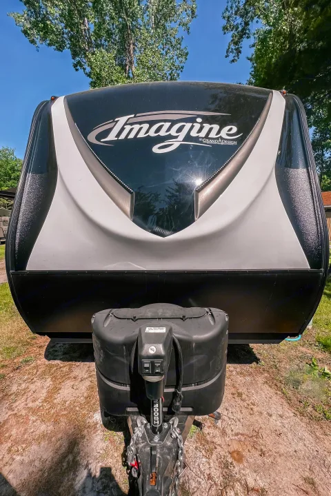 Front view of an Imagine by Grand Design travel trailer, ideal for your next RV rental adventure at a sunny campsite.. Grand Design Reflection 2021