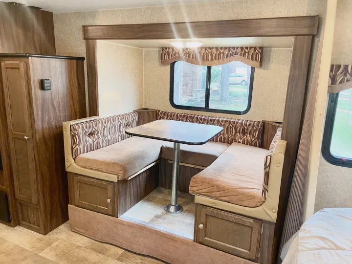 Spacious RV rental dinette featuring U-shaped seating, table, and window, perfect for dining or relaxing in your home on wheels.. Sportsmen Show Stopper 2016