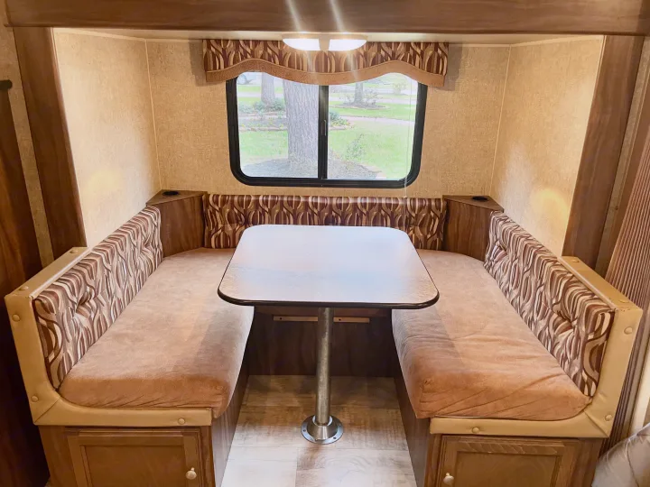RV rental dinette interior featuring patterned cushions, a window, and a central table setup.. Sportsmen Show Stopper 2016
