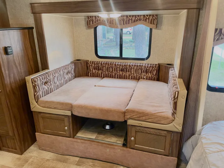 An RV rental's dinette, featuring patterned cushions, is shown converted into a comfortable bed for optimized space.. Sportsmen Show Stopper 2016