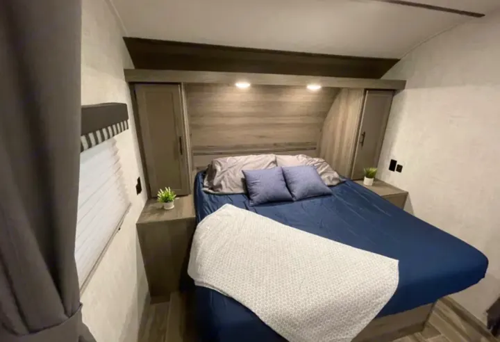 Cozy RV rental bedroom with a comfortable bed, overhead storage, and integrated lighting. Perfect for your next road trip!. Grandriver 25BH 2021