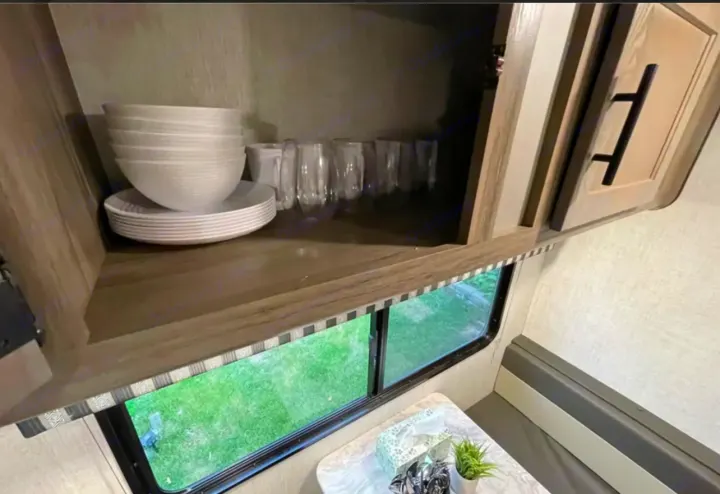RV rental: Dishes in an open cabinet above a window with a grassy view and dinette seating.. Grandriver 25BH 2021