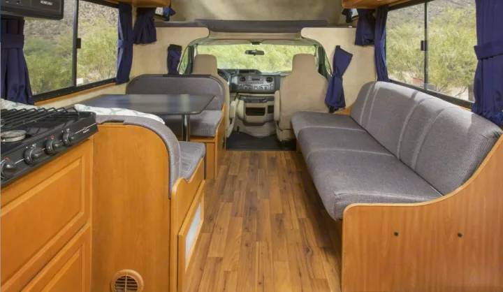 View inside an RV rental showing kitchen, dining, and sofa areas, leading to the driver's cabin.. Thor Majestic 2018