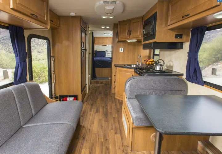 Explore this modern RV rental interior featuring a full kitchen, comfortable dinette, and cozy bedroom.. Thor Majestic 2018