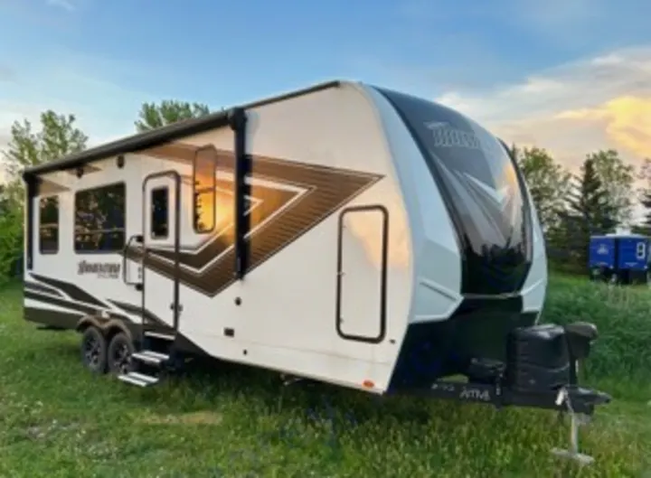 A modern white and black travel trailer RV, featuring multiple windows and an awning, ready for your next RV rental adventure.. Grand Design Momentum 2022