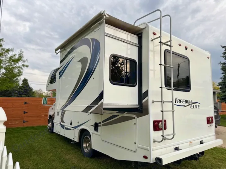 White Freedom Elite RV rental, a motorhome with an extended slide-out, parked on grass. Perfect for your next trip!. Thor Freedom Elite 2018