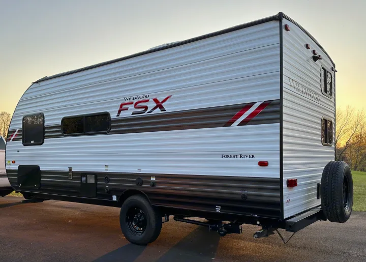 This Wildwood FSX travel trailer, light gray with black and red accents, is an ideal RV rental for outdoor adventures.. Forest River Wildwood FSX 2021
