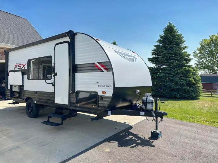Discover this white and black Wildwood FSX travel trailer. Great for an rv rental, it's parked outside on a sunny day.. Forest River Wildwood FSX 2021