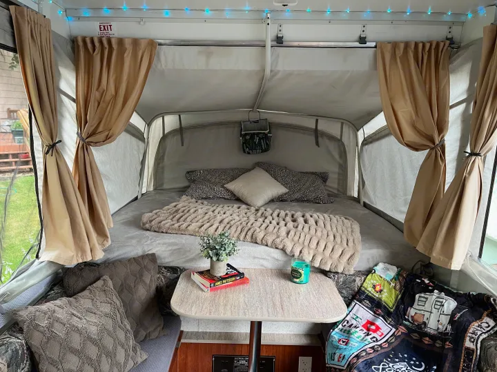 Inviting RV rental interior featuring a comfy bed, reading table, and cozy decor for a relaxing glamping or camping getaway.. Coleman Americana Utah 1995