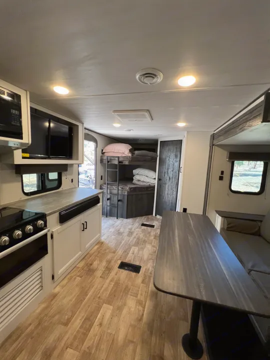 Spacious RV rental features a full kitchen with microwave, dining table, and built-in bunk beds.. Keystone RV Hideout 2022