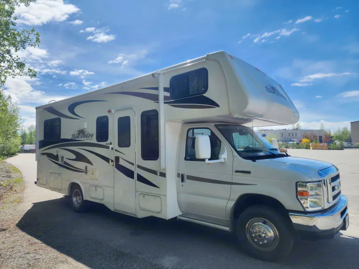 Light-colored Sunseeker Class C RV rental parked on an asphalt lot under a blue sky. Perfect for your road trip!. Forest River Sunseeker 2012
