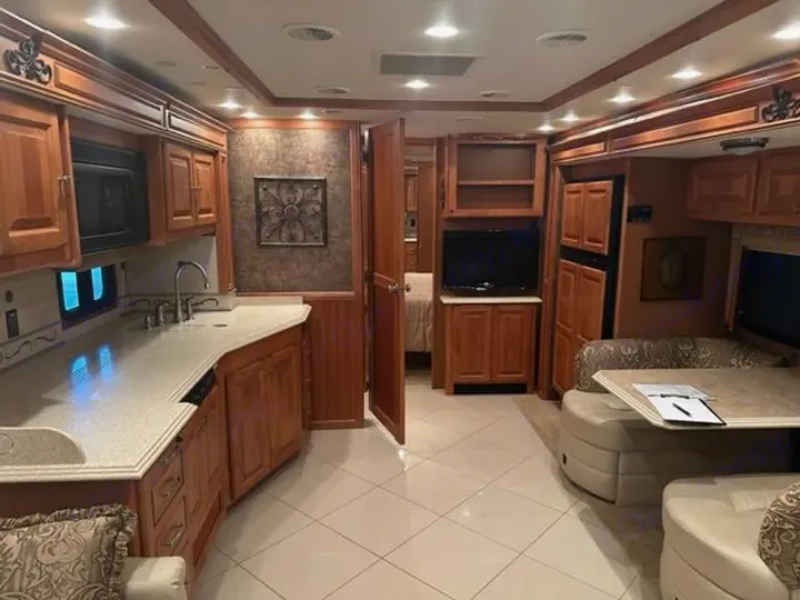 Spacious RV rental interior featuring a full kitchen with microwave & sink, comfortable dining/living area, wood cabinetry, and tiled floors.. Phaeton Phaeton Motorhome 2011