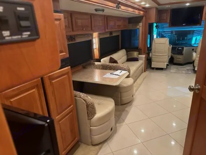 Spacious rv rental interior featuring light wood cabinetry, comfortable sofa seating, a table, and tiled floors.. Phaeton Phaeton Motorhome 2011