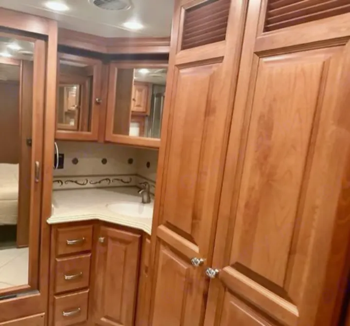 RV rental: Light wood bathroom vanity featuring a sink, mirrors, and ample storage. A clean and functional RV interior.. Phaeton Phaeton Motorhome 2011