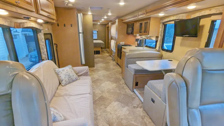 Spacious RV rental interior featuring a living area with a sofa, kitchen, dinette, and a bedroom visible in the rear.. Thor Windsport 2016