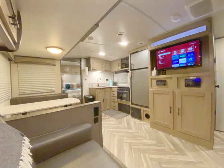 Modern RV rental interior with kitchen, dinette, TV, and a glimpse of the bedroom.. Shadow Trailers 277BHS 2020