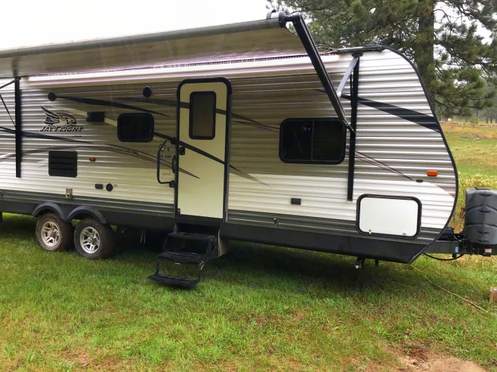Spacious Jay Flight travel trailer RV rental, parked on grass. Awning extended with lights, ready for your outdoor adventure.. Jayco Jay Flight 2015