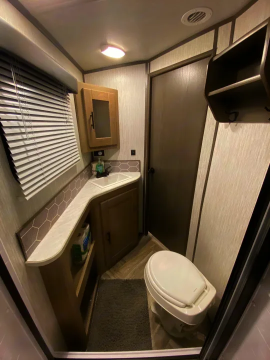 Step inside this modern RV rental bathroom, featuring a practical sink, toilet, and ample storage for your travels.. Shadow Trailers 277BHS 2020