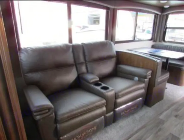 Inside an RV rental: two comfy recliners with cupholders and a dinette, offering a relaxing travel space.. Keystone RV Cougar 2022