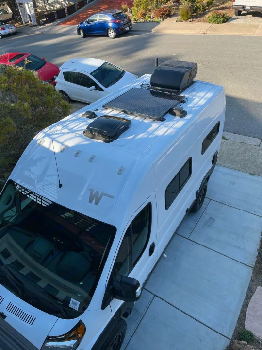 Bright white RV rental van, viewed from above, featuring rooftop solar panels and an AC unit.. Winnebago Solis Pocket 2022