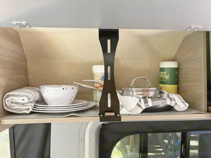 Organized RV rental cabinet, neatly stocked with essential kitchenware: plates, bowls, pots, pans, and towels.. Winnebago Solis Pocket 2022