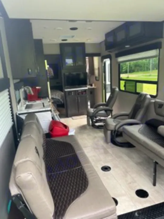 Spacious RV rental interior with modern gray seating, TV, and a view to the bedroom, ideal for travel adventures.. Grand Design Momentum 2022