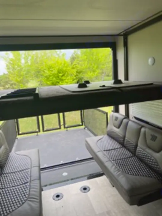 RV rental toy hauler: Spacious interior garage with convertible sofas, an elevated bunk, and an open ramp/patio for views.. Grand Design Momentum 2022