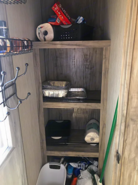 RV rental storage/pantry: well-organized shelves with kitchen essentials like foil, paper towels, and cleaning supplies.. Forest River Cherokee Arctic Wolf 2020