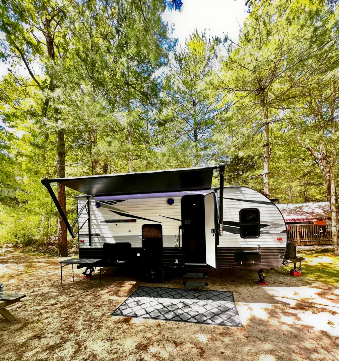 RV rental travel trailer with extended awning at a sandy forest campsite, ready for your outdoor getaway.. Independence Trail 188DBK 2022