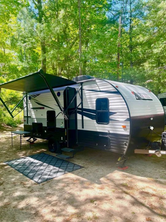 This **RV rental** is perfectly set up at a serene, tree-lined **campsite**, featuring an extended awning for shade and an outdoor mat.. Independence Trail 188DBK 2022