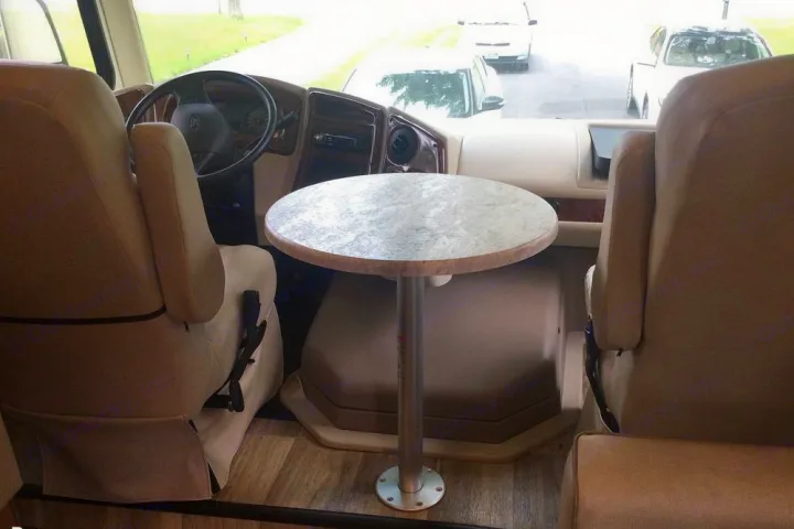 RV rental's front interior. View showing the cockpit with two beige captain's chairs and a round table for convenience.. Coachmen Pursuit 27DS 2019